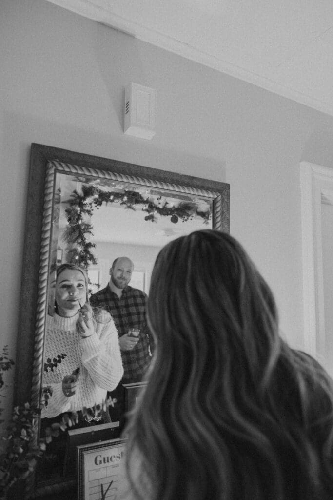 couple together at home, husband watching as his wife applies lipstick